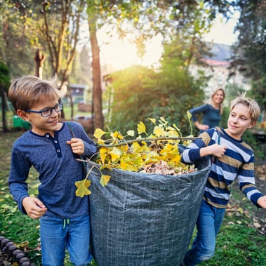 Kids earning money by doing chores, carrying leaves