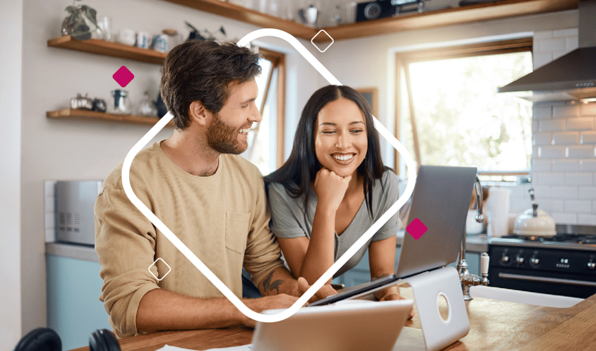 Couple sitting at table looking at laptop