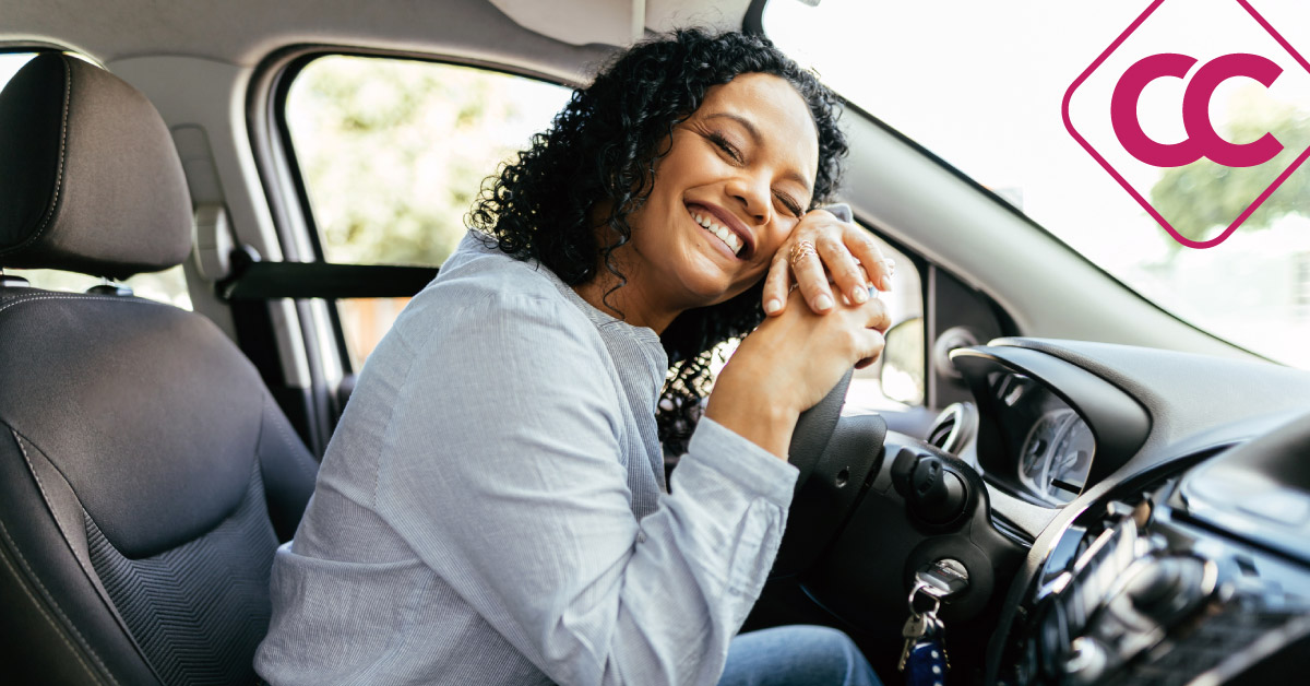 Woman sitting in driver's seat hugging the wheel