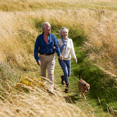 Couple walking dog through park