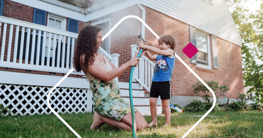 Family playing in front of house with hose