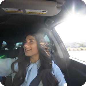 woman-smiling-in-car-interior-with-sunlight-streaming-through-window
