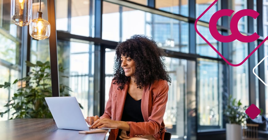 A woman sitting at her laptop, typing and smiling