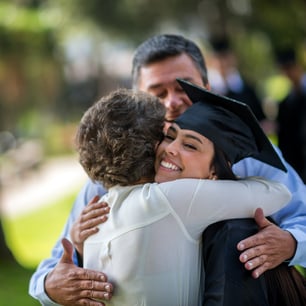 Proud parents hugging their graduating daughter in cap and gown