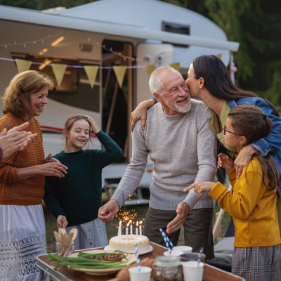 A family celebrating their grandfather's birthday by the RV