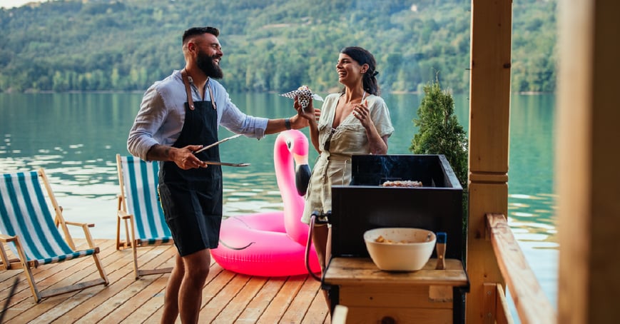 Couple grilling on deck by lake