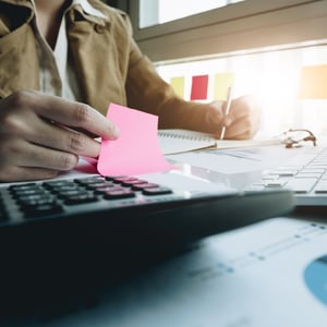Man calculating with sticky note and pen