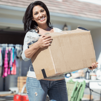 Woman at garage sale holding a box of clothing