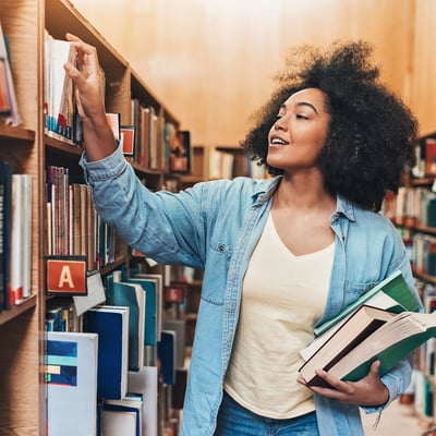 college student in library putting book on shelf